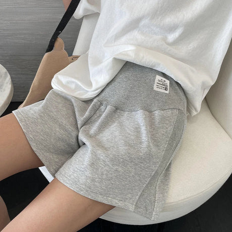 Woman wearing plus size adjustable maternity shorts in grey, designed for comfort during summer pregnancy.