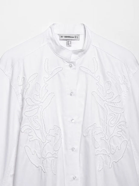 Elegant white embroidery shirt with stand collar and button closure, showcasing intricate floral patterns.