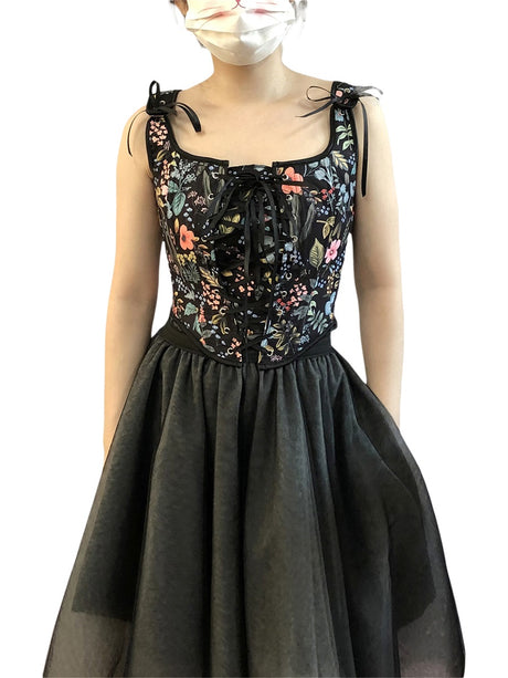 Woman wearing a floral retro corset cropped camisole party top with a black skirt, featuring a lace-up front and adjustable straps.