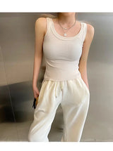 Model wearing RetroRib™ 90s Vintage ribbed tank top in light color, paired with comfy white sweatpants, showcasing streetwear style.