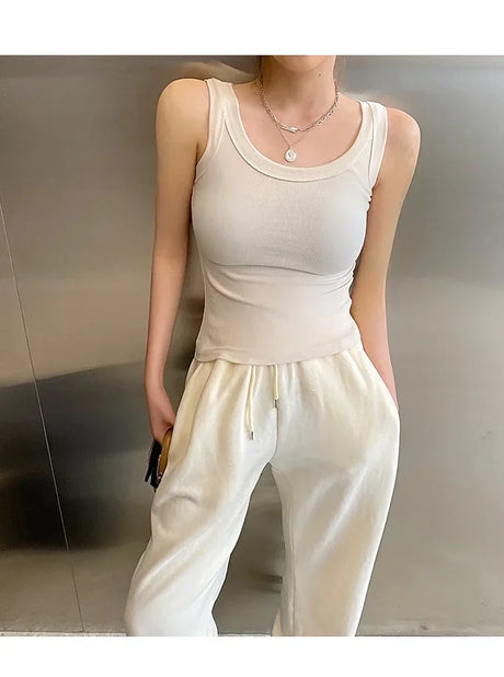 Model wearing RetroRib™ 90s Vintage ribbed tank top in light color, paired with comfy white sweatpants, showcasing streetwear style.