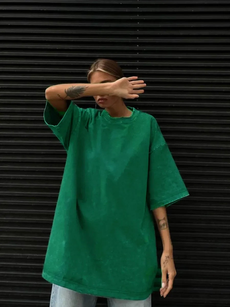 Model wearing a loose-fitting green casual t-shirt against a textured black background.