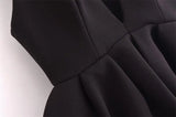 Close-up of elegant black fabric detail from a V-neck women tank top, showcasing its pleated design and smooth texture.