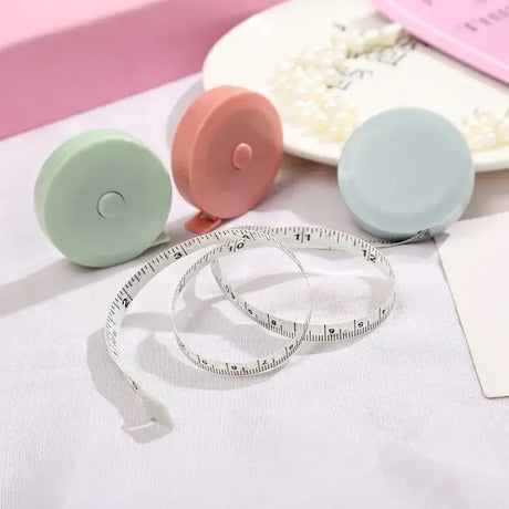 Colorful mini measuring tapes in green, pink, and blue laying on a soft surface, perfect for accurate measurements.