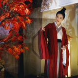 Swordsman Hanfu costume in wine red worn by a woman, set against a backdrop of vibrant autumn leaves.