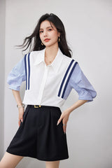 Woman wearing StripeMuse™ Colorblock Chiffon Shirt with blue striped sleeves and black shorts, showcasing a casual office look.