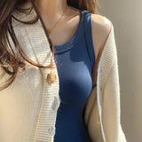 Stylish woman wearing a blue padded spaghetti camisole, layered under a cream cardigan, perfect for summer.