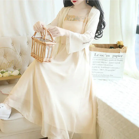 Elegant woman wearing a floral 2-piece Hanfu summer dress, holding a basket, sitting in a bright room.