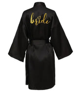 Team Bride satin kimono robe in black with golden 'bride' lettering on the back, ideal for bridal parties.