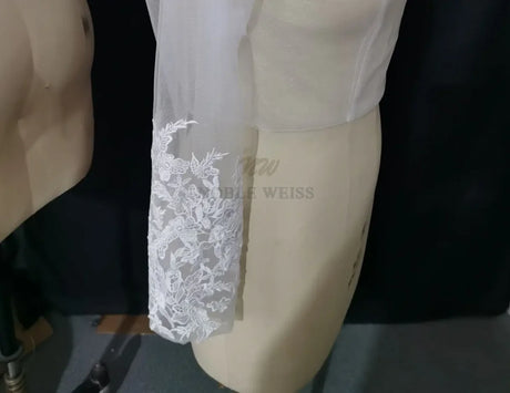 Lace Bridal Bolero featuring long sleeve appliques on a dress form, showcasing elegant embroidery details.
