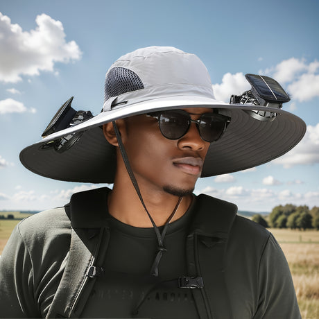 Man wearing a sporty men's sun hat equipped with solar fans outdoors under a clear blue sky.