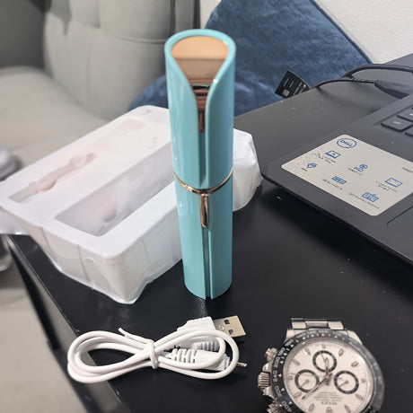 USB rechargeable mini hair trimmer for women in teal color with USB cable and packaging on a desk.