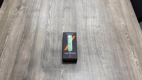 Body hair trimmer for men and women in packaging on a wooden table, featuring MAXGROOM brand and rechargeable battery.